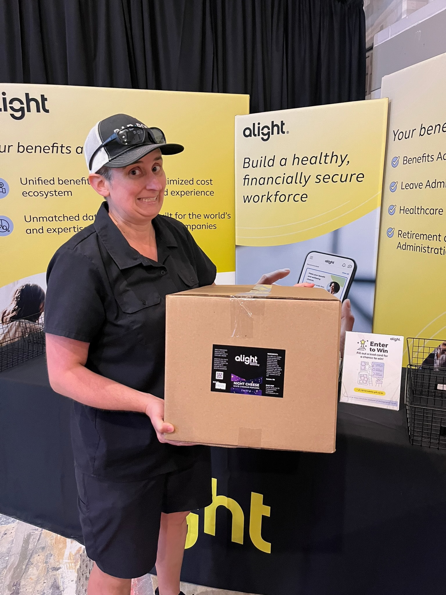Katie holding a custom-branded Rad Pop popcorn box at an Alight event booth